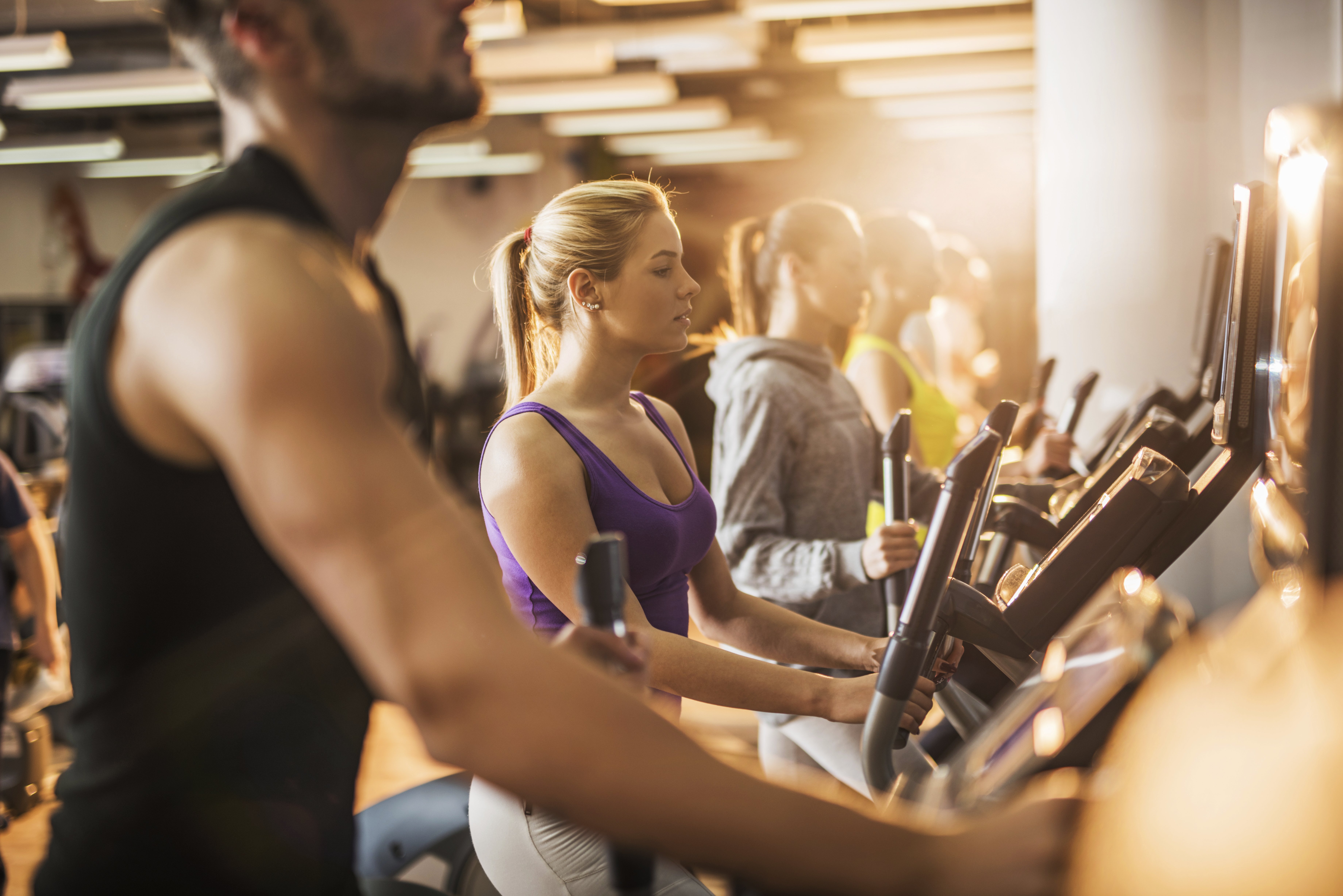Group of people exercising on exercise machine in a gym.