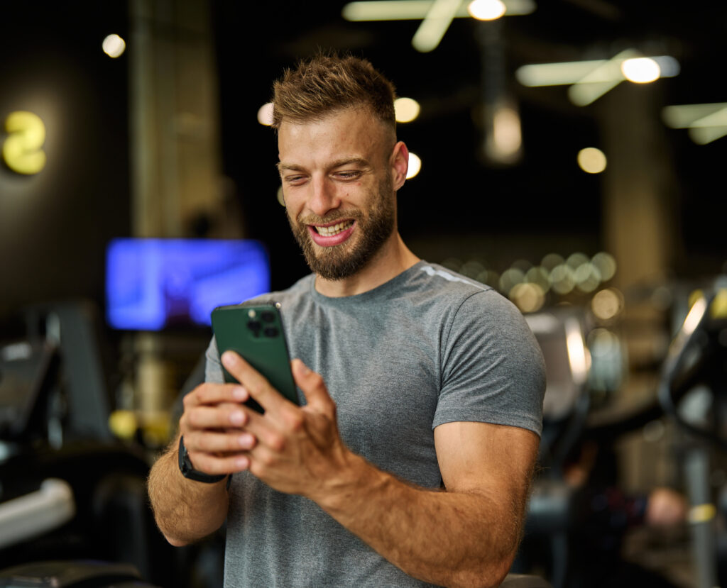Gym owner looking at mobile phone smiling
