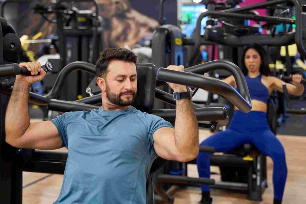 People training on gym machines showcasing modern equipment and gym branding focused on strength and performance.