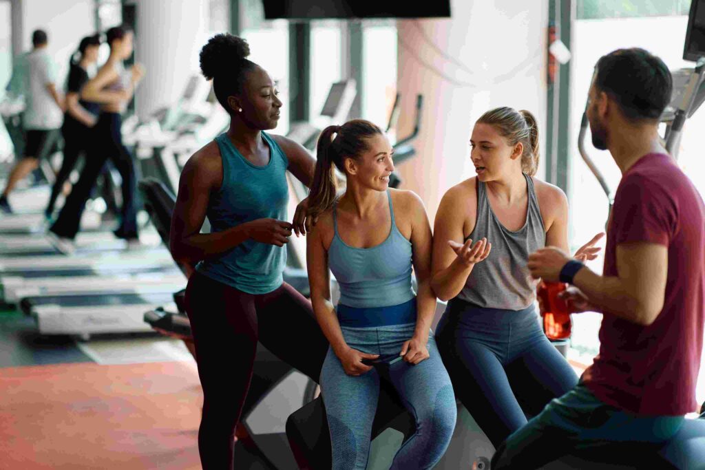 Gym members socialising during workout break reflecting positive gym culture and community branding.