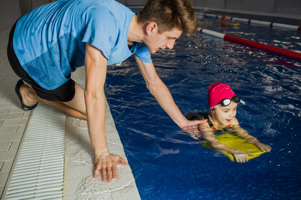 Swimming teacher helping a child in the pool
